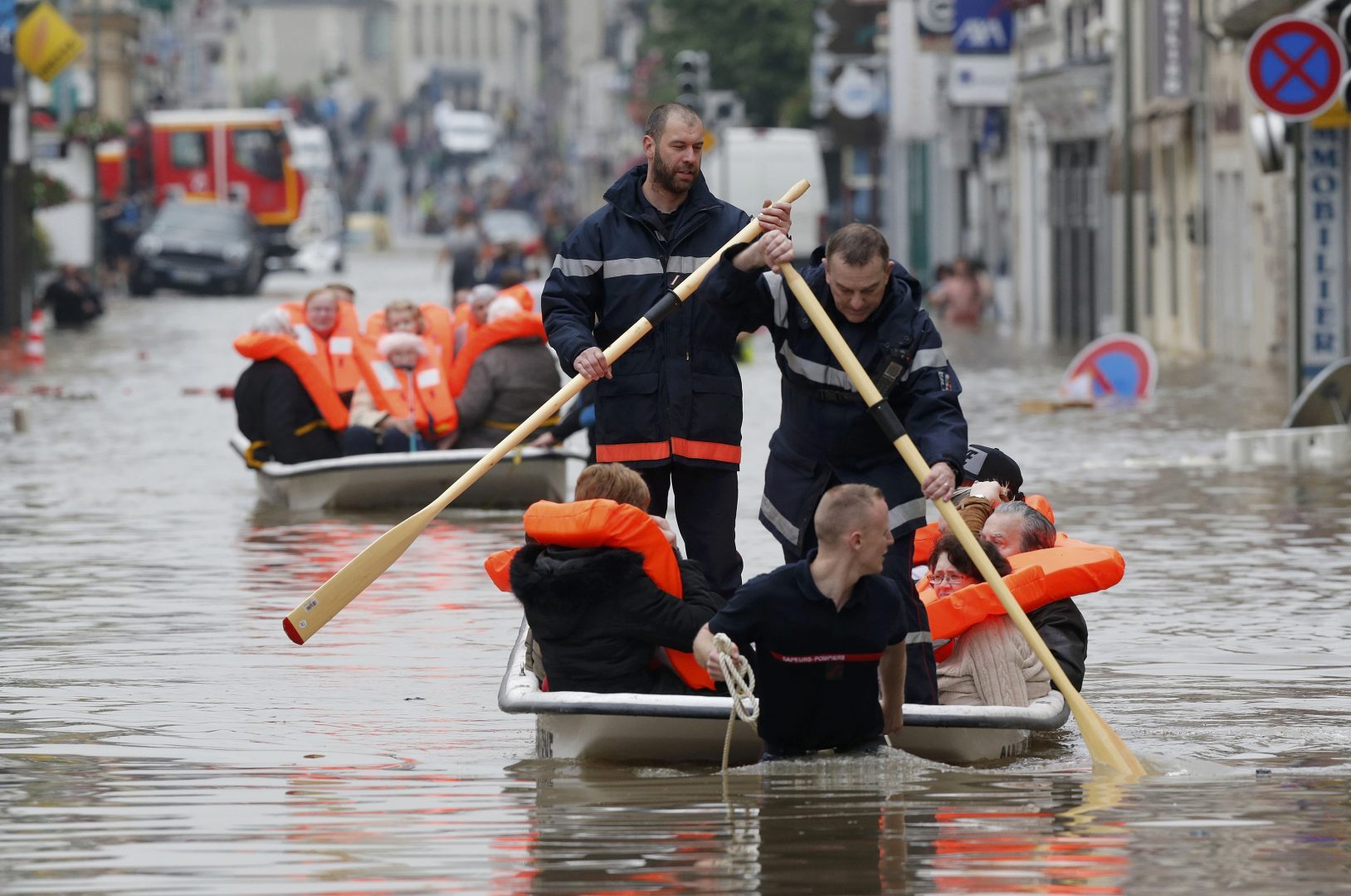 French firefighters on small boats evacuate residents from a flooded area after heavy rainfall in Nemours